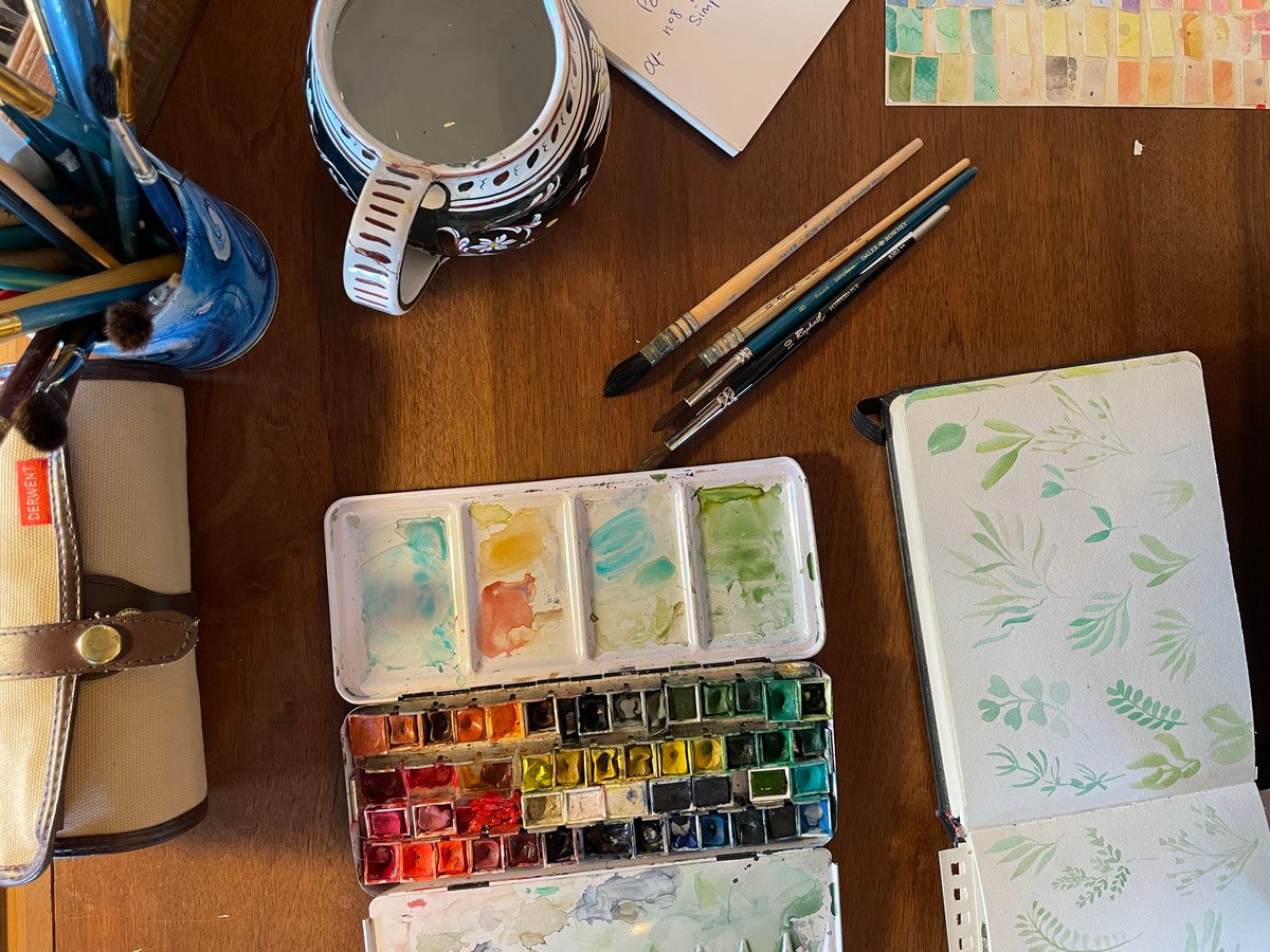 Godets d’aquarelle et carnet de travail dans l’atelier de Carole